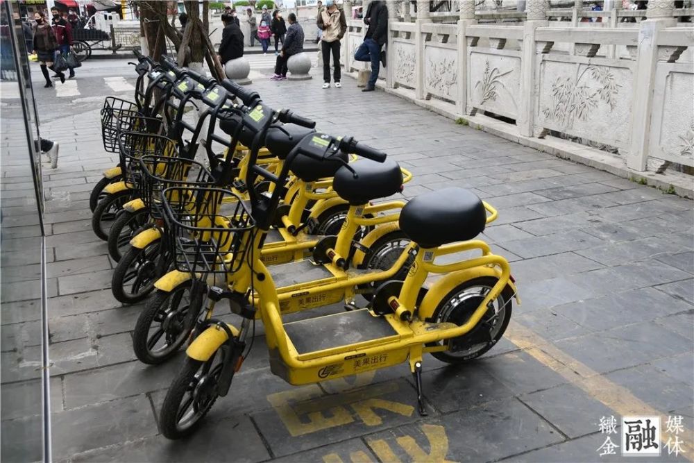 一款黄色车身,名为"美果出行"的共享电单车整齐停放在织金的各大街道