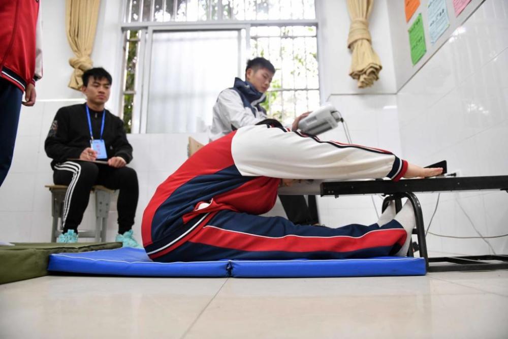 双腿平伸靠拢,双手平举向前往下压腰,推动前方的滑尺,推动距离越远