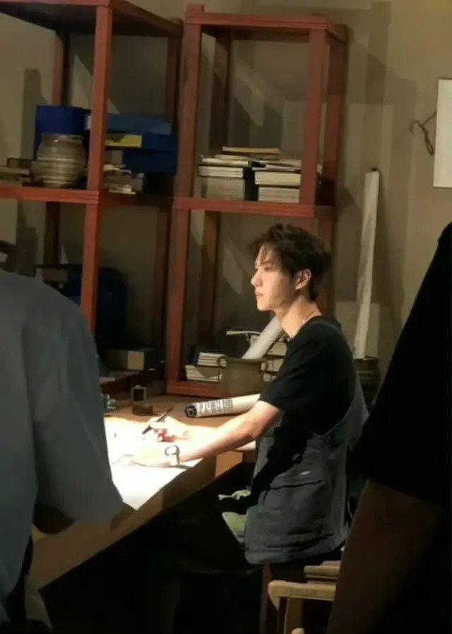 工作人员拍到王一博在工作闲暇时练习书法,他十分安静地坐在一旁写字