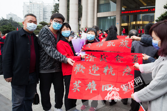 沙坪坝人民医院谷晓琴(左三)的家人带着自己写的横幅前来迎接.