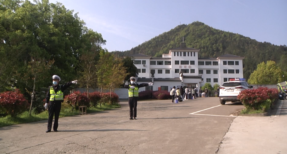 在婺源县江湾中学校门口,交警正在有序疏导来往车辆,学生们自觉间隔一