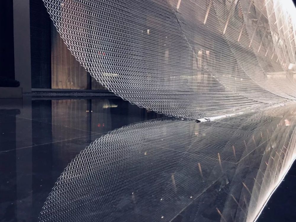 装置高度四米,金属幕帘或围合或遮挡,表面有光泽垂感,光会投射形成灰