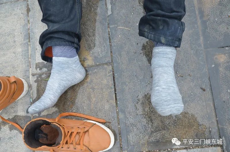 中等身材,短发,上穿着黑色外套,下穿身深蓝色牛仔裤,脚穿灰色袜子