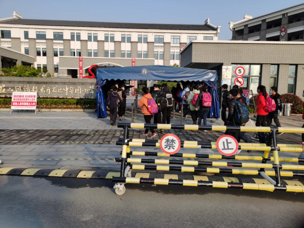依次测量体温无异常后,才能入校学生们在校门口排队也是中华园小学新