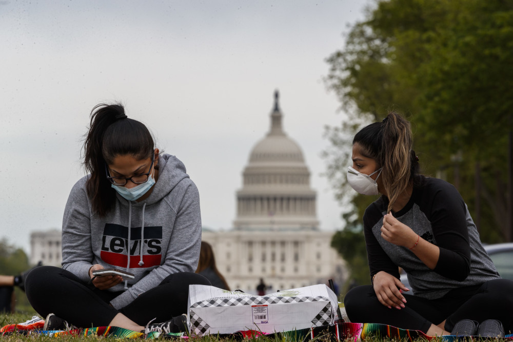 4月19日,美国首都华盛顿,两名戴口罩的女子坐在国家广场草坪上.新华社