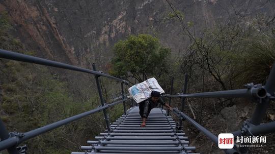 直击悬崖村今日第一位搬家人女子背着宝贝在最陡峭梯段缓慢下山
