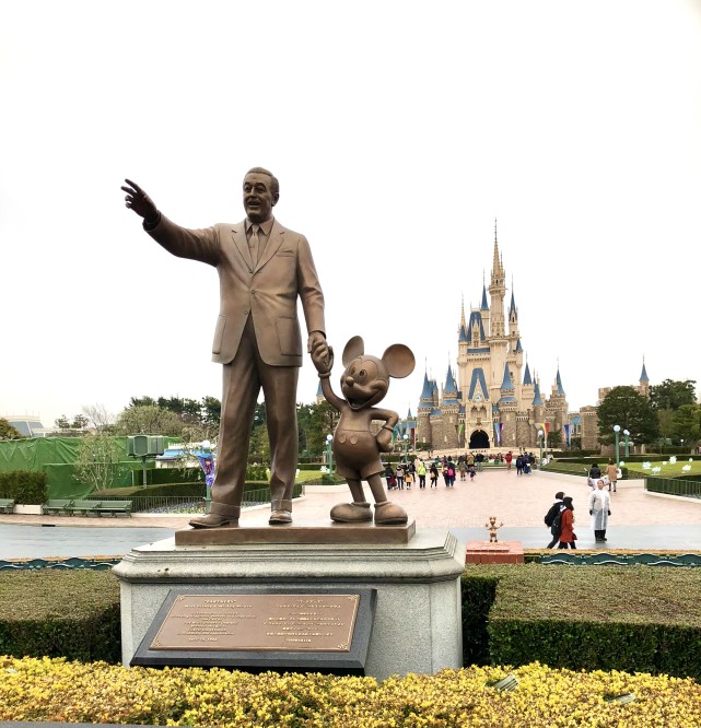 在巨大的主城堡前,沃特·迪士尼(walt disney)正牵着米奇的手迎接着
