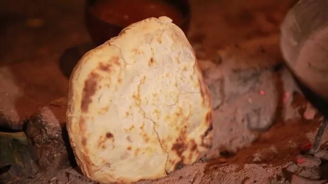 面饼翻过两三次面,外层开始变硬,这时就要转移阵地,被埋进火塘的柴灰