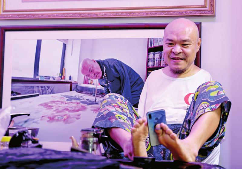 重庆口足画家黄国富失去双臂用双脚画出一条幸福之路