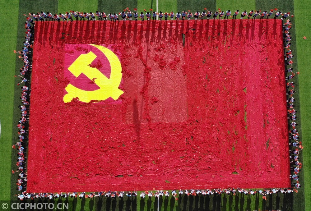 小学生用红领巾和党徽图案拼成巨幅党旗,庆祝建党99周年
