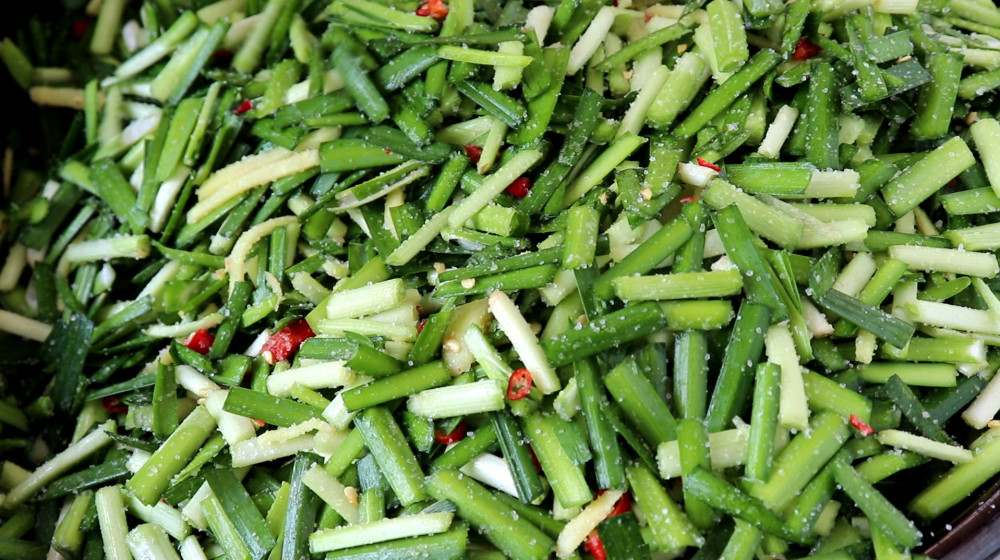 5,这会韭菜腌好了,然后把韭菜装进提前准备的玻璃罐里面.