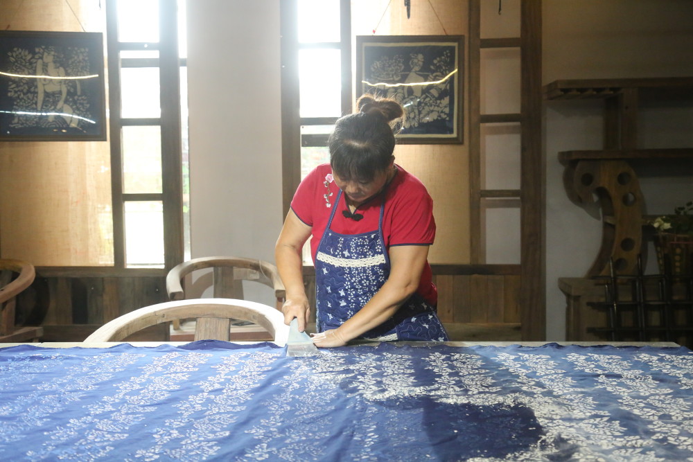 在湖南蓝印文化创新孵化基地,工人在晾晒完毕的布料上铲去石灰豆浆.