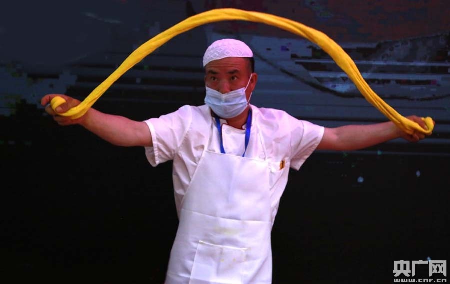 现场演示拉面技艺(央广网记者 张雷 摄)拉面师傅向现场观众展示三色面