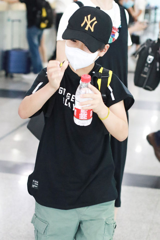 郑钧带儿子搭机造型很休闲 萌娃郑熙岳忙拧瓶盖笑眼可爱