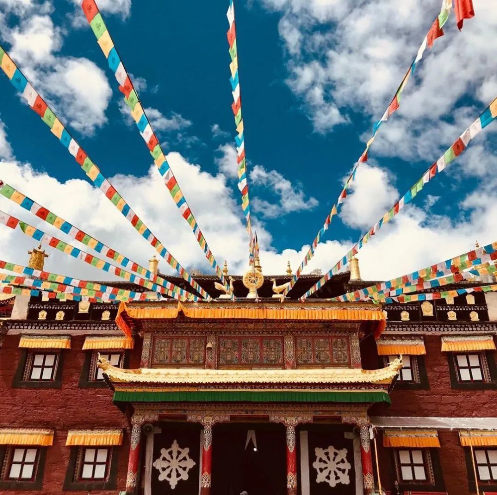 这儿坐落着 一座神圣的塔公寺, 宏伟壮观的寺庙,在巍峨雪山的映衬下
