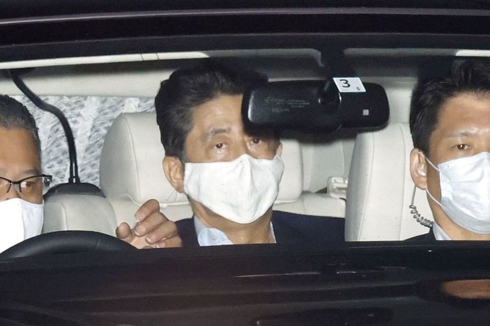 日本首相安倍晋三戴着口罩乘专车抵达东京都信浓町的庆应大学医院