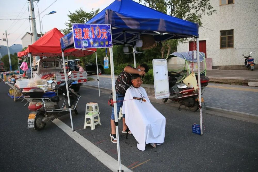 16日下午6时,人来人往的夜市中,一家写有"10元理发"的摊位旁已经有不