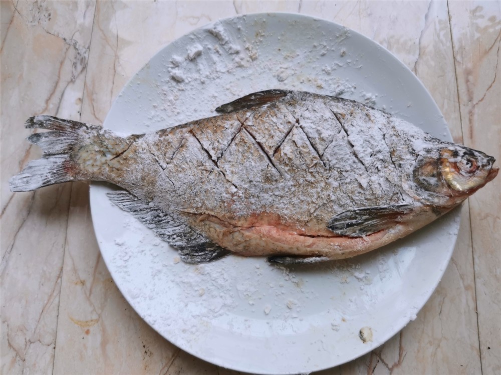 把鱼的两面都均匀的涂上一层干淀粉,锅内加入油烧热,下入鳊鱼炸制,先