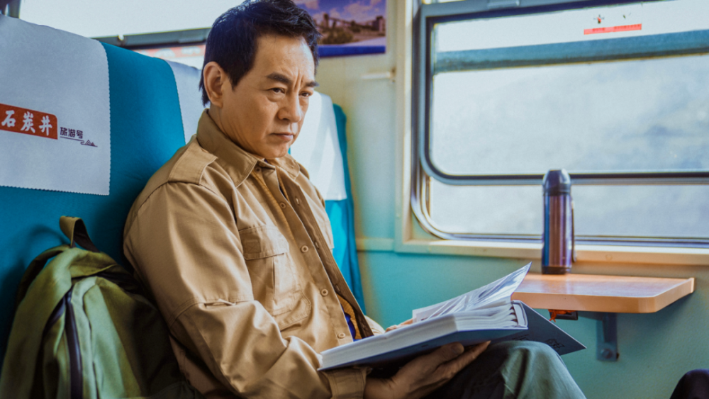 穿过城市,穿过田野,穿过高楼大厦……绿皮小火车上,郭建国坐在车厢里