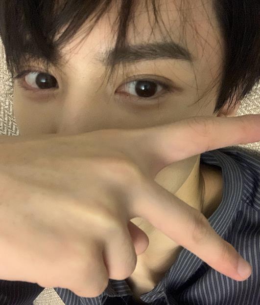 陈哲远深夜坐沙发自拍一边做比心动作一边露出一双可爱的眼睛