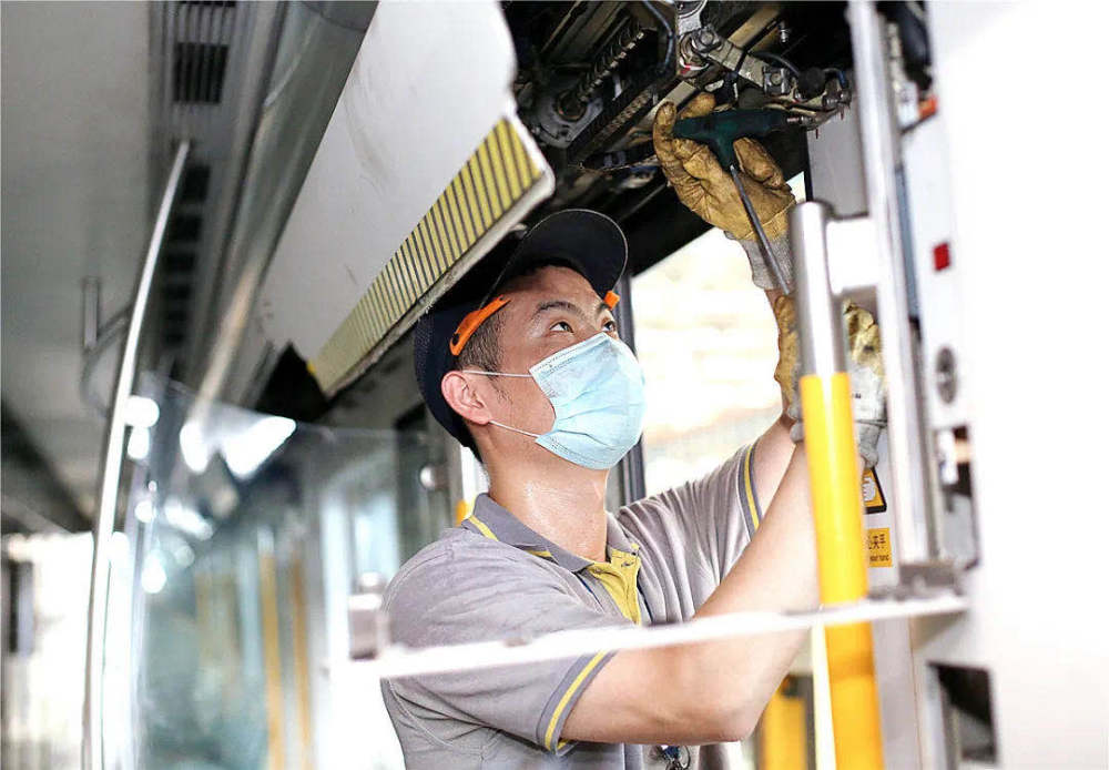 高温下检修地铁列车:双手举着中顶板,连汗水流到眼角都无法擦拭