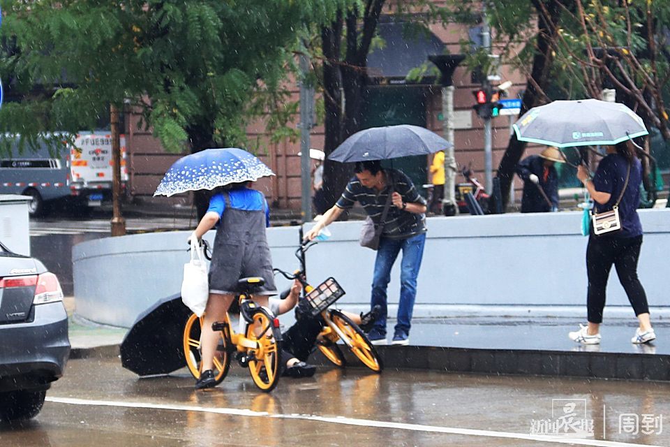 年轻女士雨中撑伞骑车摔倒,切记,撑伞骑车很危险