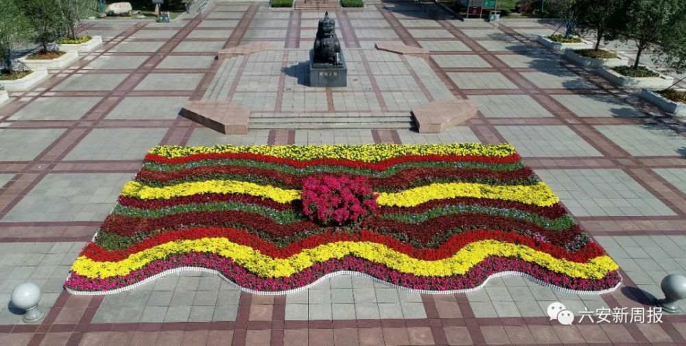 在皋城广场的獬豸像前,各色花卉以波浪形一圈圈摆放整齐,黄的,紫的,绿