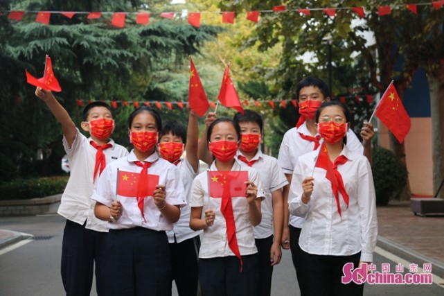 疫情当前,学生们特意戴着印有国庆元素的口罩,挥舞国旗,欢庆抗击疫情