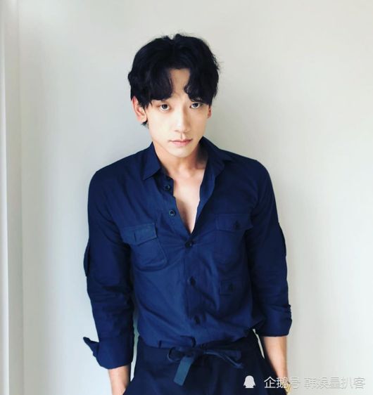 照片中,rain身穿蓝色衬衫和裤子,同色搭配,坐在椅子上.