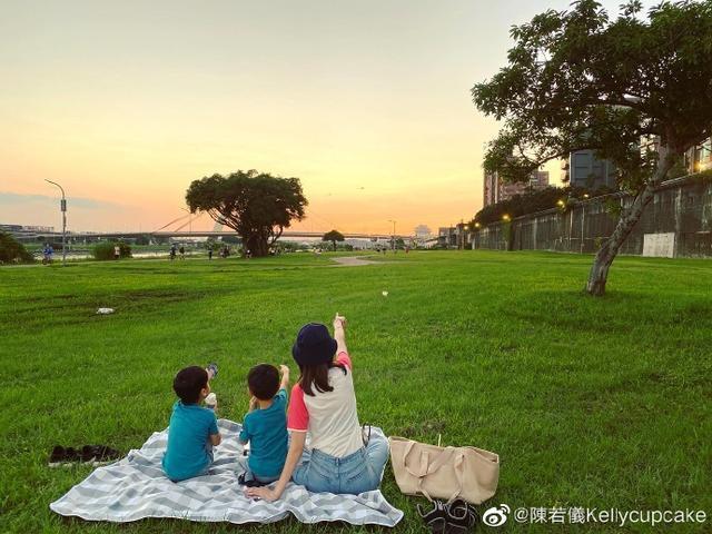 陳若儀在草坪鋪上墊子,與孩子們並排看夕陽,三人還用手指著