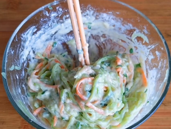 5.锅里刷油,用勺子舀上一勺菜糊,然后整理成圆形,表面撒上芝麻增香.