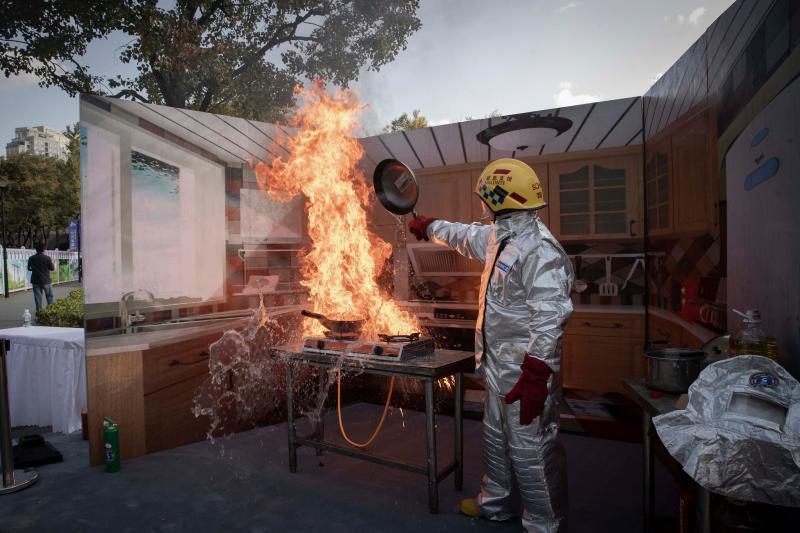 一名消防员在演示厨房油锅着火后泼水灭火的后果.