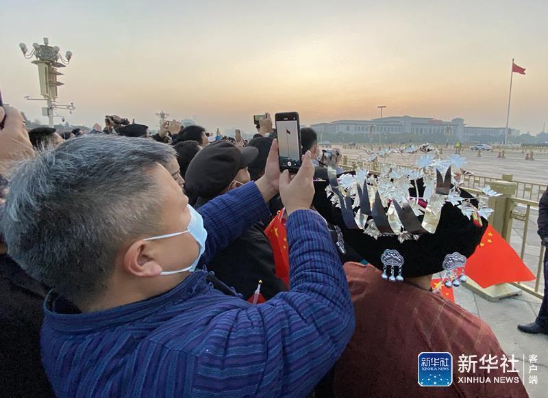 11月6日，湖南省湘西土家族苗族自治州花垣县十八洞村的首任扶贫工作队队长龙秀林（前）在天安门前观看升国旗仪式后用手机拍照留念。新华社记者 李贺 摄