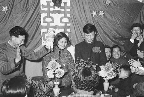 图为春节期间结婚的场景,小两口在婚礼仪式上接受朋友们的祝贺.