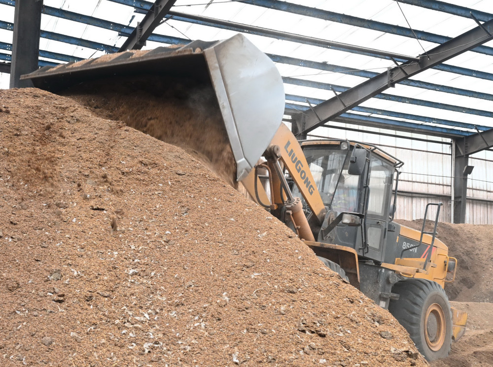 工人在光泽县的福建省凯圣生物质发电有限公司的谷壳和鸡粪混合物堆料
