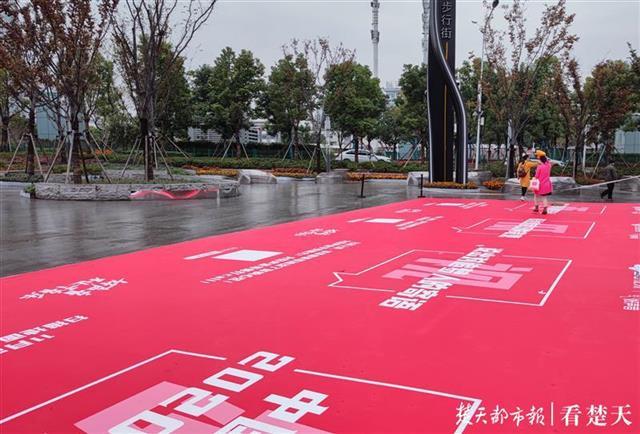 几个工作人员正冒着小雨,把红色巨幅广告纸贴在步行街街口路面上,到了