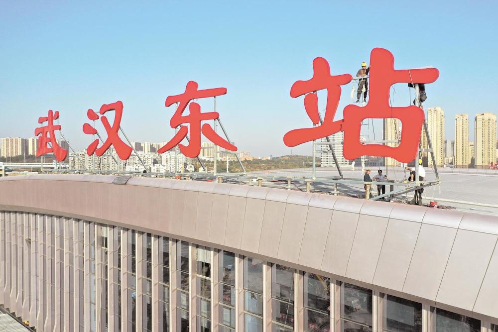 武汉东站站名挂牌,施工人员将"武汉东站"四个红色大字安装在西站房