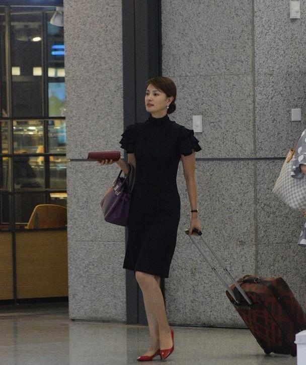 照片中出现在机场的刘芳菲选择了一件深蓝色的连衣裙,贴身的设计完美