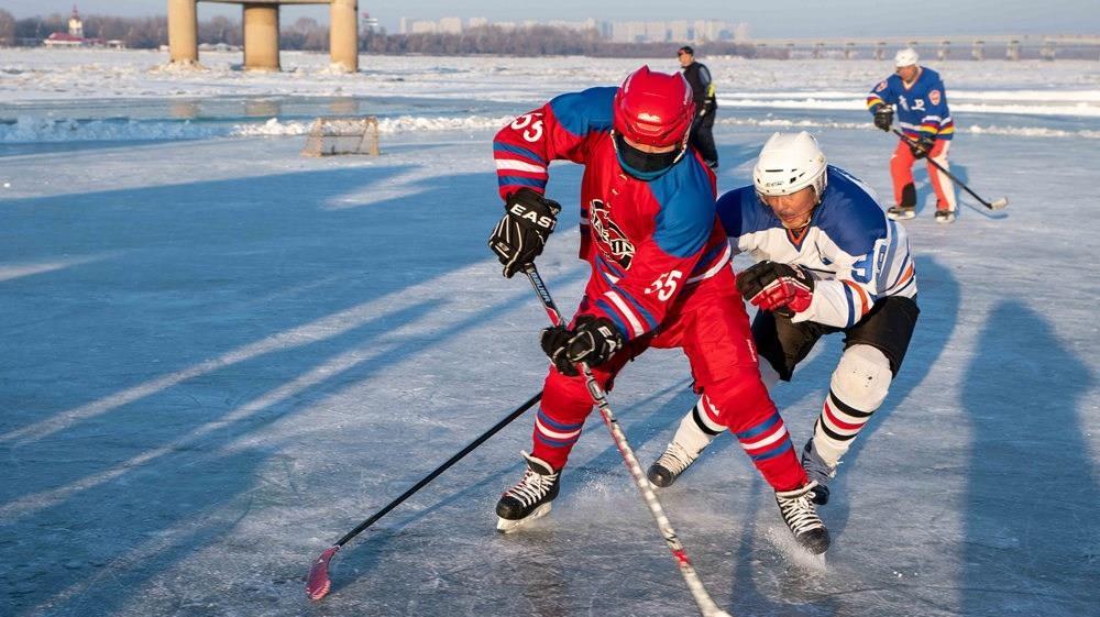区斯大林公园附近江面上,有一群穿戴着专业护具热火朝天打冰球的老人