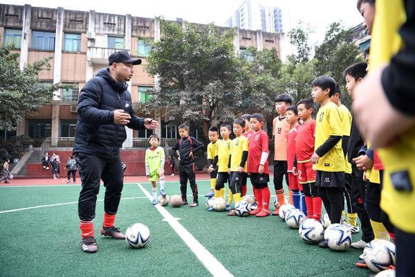 12月9日,重庆市沙坪坝区双碑小学足球老师蒋琦(左一)在给足球队员们