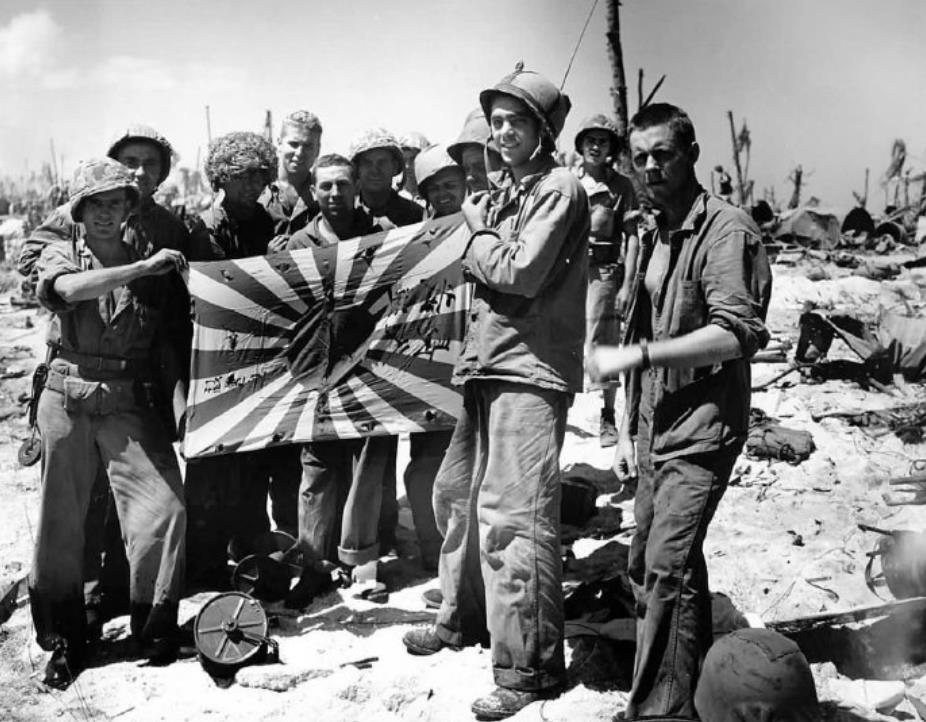 二战时期,美国海军陆战队员合影,日本军旗成为最好战利品