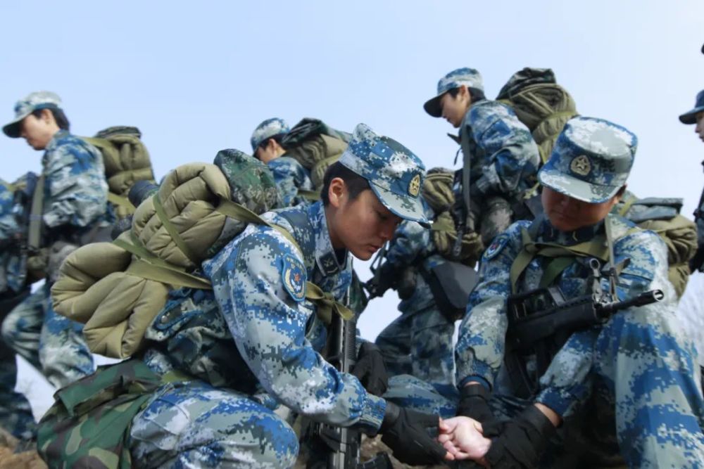 拉练途中,班长在帮助战友处理脚上磨出的水泡.