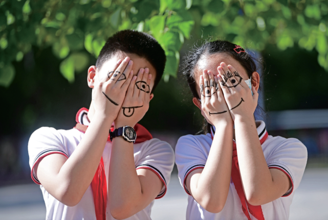 日,辽宁,沈阳农业大学附属小学六年级的两个学生在手上绘制了笑脸图案