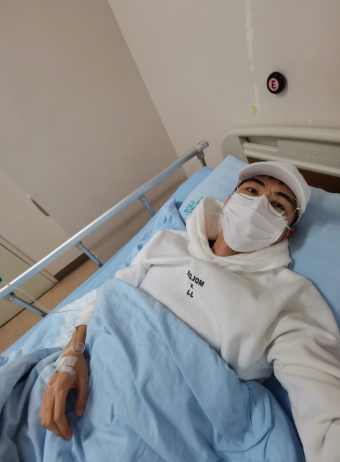 陈学冬躺在单人病床挂吊水,手上扎着输液管,一只手挂吊水,另一只手还