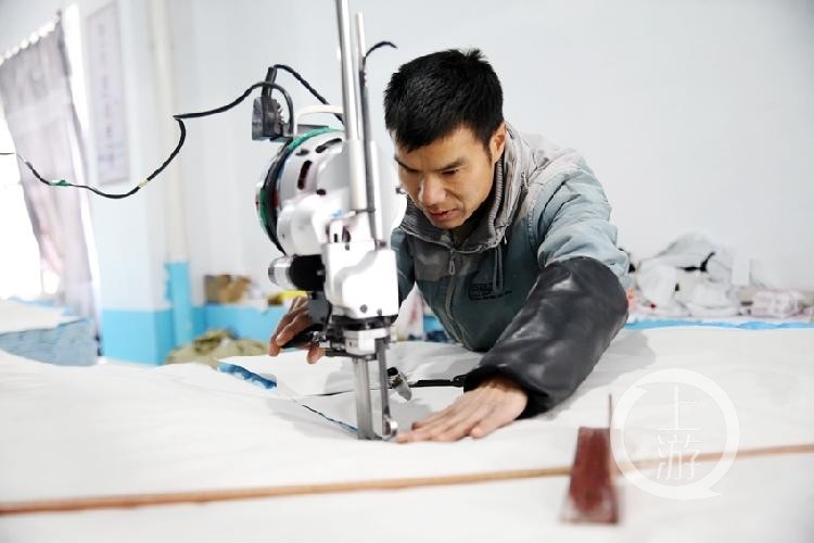 工人在服装厂扶贫车间裁剪服装.工人在工厂内忙碌.