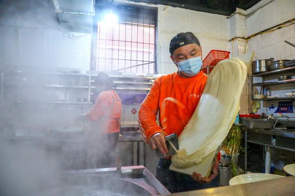 "无声面馆"的店员正在制作刀削面