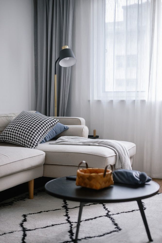 米白色的l型布艺沙发柔和而内敛,线条感极强的落地灯,洋溢着极简主义