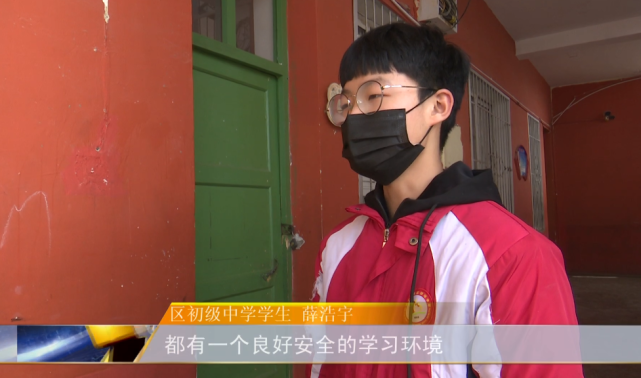 在区初级中学门口,学生们秩序井然地走进体温检测通道测量体温,安保