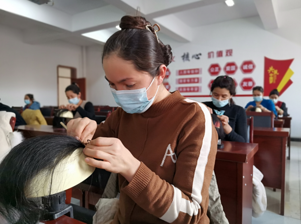 1月10日,在五o团十一连多功能活动室内,妇女们正忙着学习编织假发