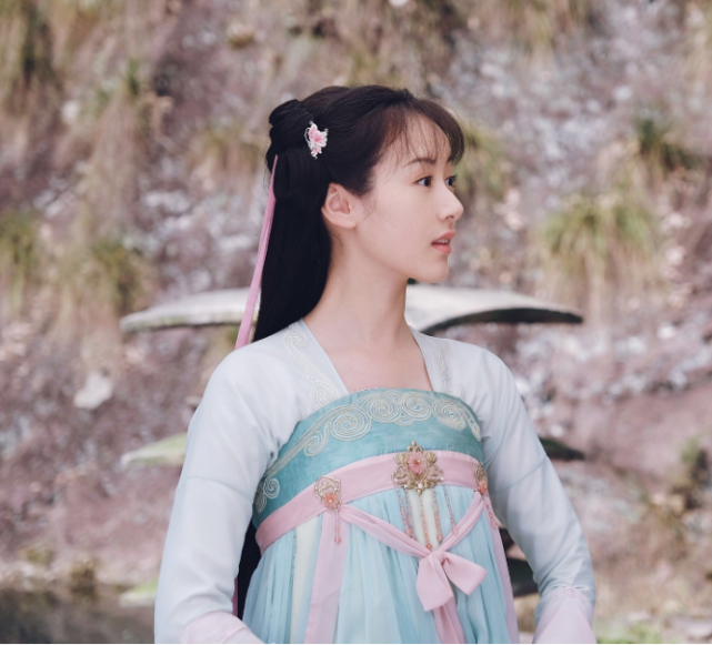 我们可以看到袁冰妍身着一身粉蓝相间的绫罗绸缎,拿着一把小圆扇,在